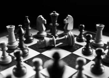 A captivating black and white photo of a chess game with fallen king piece, symbolizing defeat.