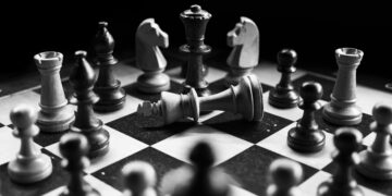 A captivating black and white photo of a chess game with fallen king piece, symbolizing defeat.