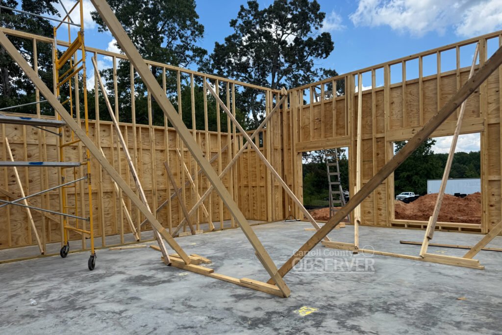 Interior construction framing of Carroll County 911 office in Huntingdon, Tennessee, showing wall studs and work areas.