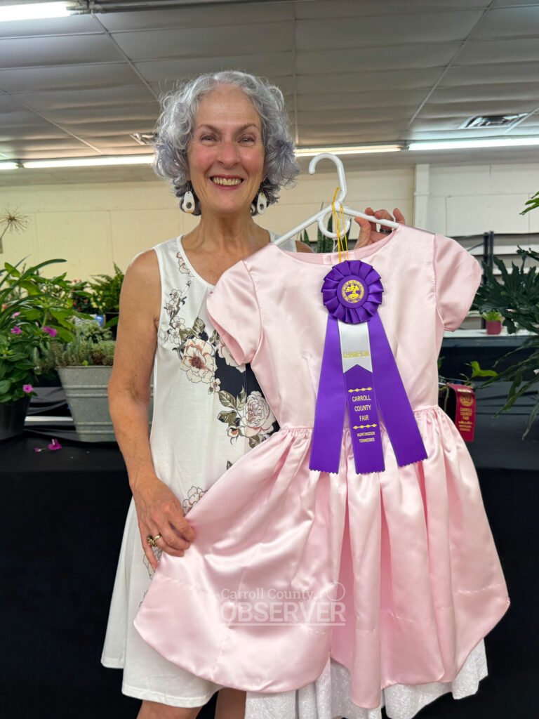 Debbie Hartman of Yuma stands with her purple ribbon-winning girl’s dress entry at the Carroll County Fair.