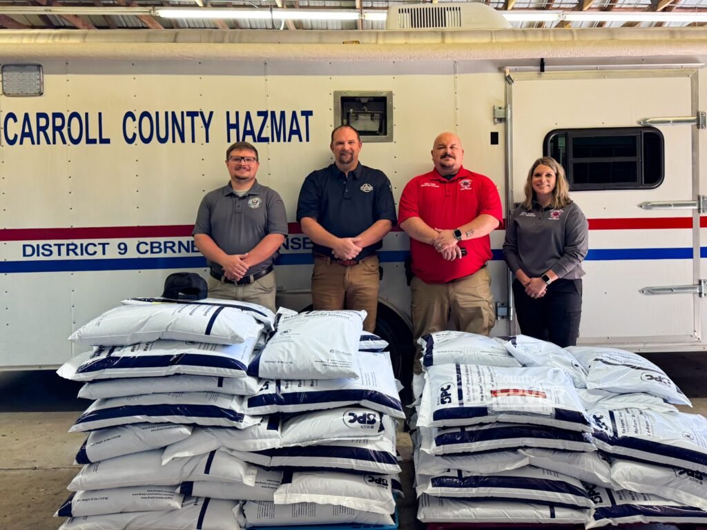 Carroll County officials stand with two pallets of oil dry donated by Ozone Environmental Services to support local hazmat operations. Pictured are EMA Director Trevor Foster, Ozone Coordinator Andy Kimbrell, Fire Chief Jonathan Gaskins, and Administrative Assistant Anna Wheet. Photo by Jesse Joseph/Carroll County Observer.
