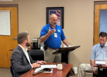 Chief Deputy Joel Pate speaks at a podium while Carroll County Mayor Joseph Butler listens at the Commission meeting. Pate explained that a diagnostic review is the first step toward safety improvements at the Harris Road railroad crossing. Photo by Jesse Joseph/Carroll County Observer.