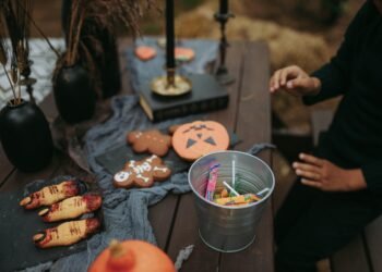 A festive Halloween setup with sweets, cookies, and spooky decorations on a wooden table.
