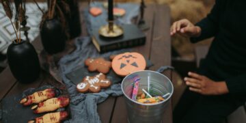 A festive Halloween setup with sweets, cookies, and spooky decorations on a wooden table.