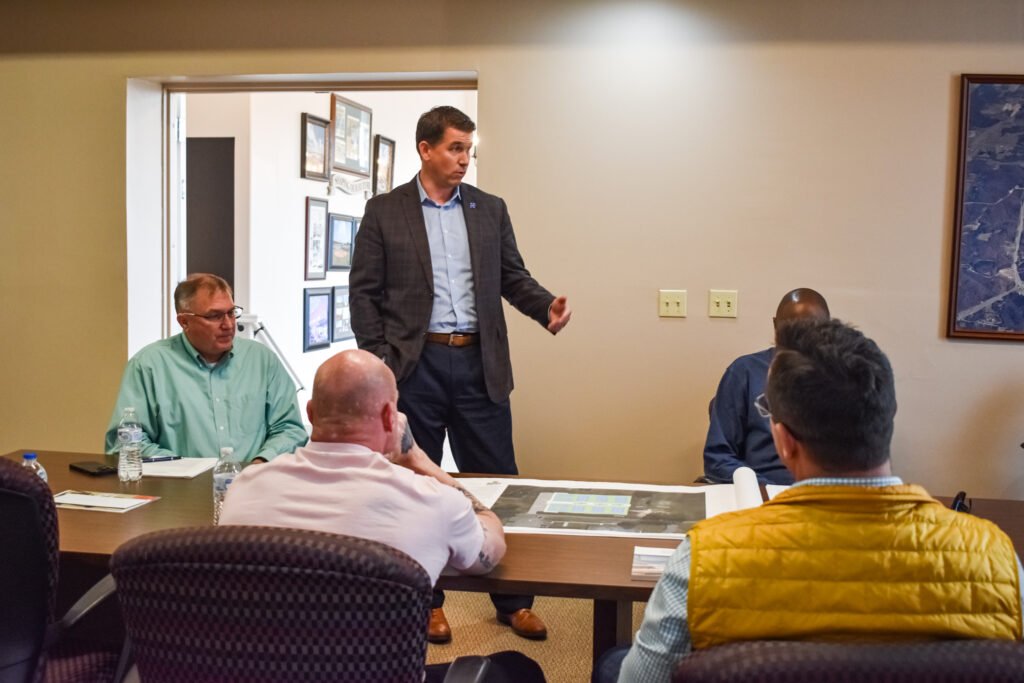 Dr. Jonathan Kee standing and gesturing while presenting architectural plans for tennis and pickleball courts to council members.