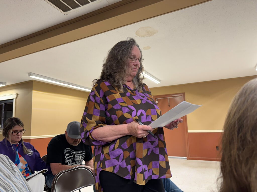 Marian Herndon stands and reads from a document during public comment at the Atwood town meeting.