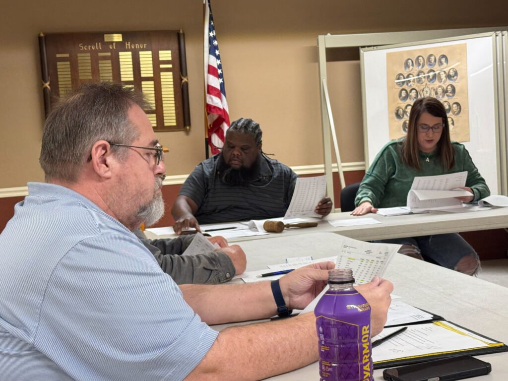 Three officials review budget documents at the board table during the Atwood town meeting.