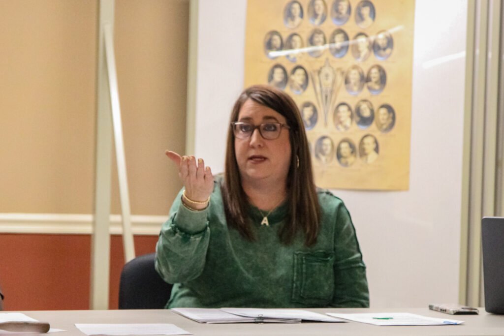 City Recorder Amanda Browning speaks at the board table with her hand raised during the Atwood town meeting.