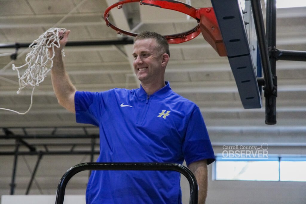 HMS Fillies head coach David Wilkins holding up net after cutting ceremony.