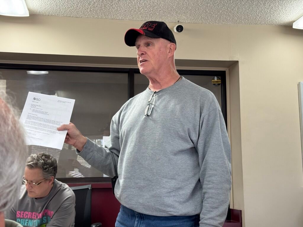 Hollow Rock Assistant Fire Chief Bob Dill stands and holds the ISO rating report while addressing the board at the March 17 meeting.