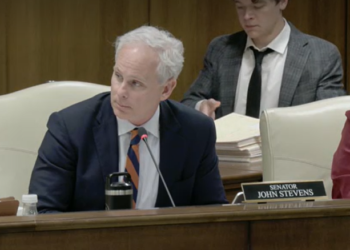Sen. John Stevens sits at a committee table with his nameplate visible.