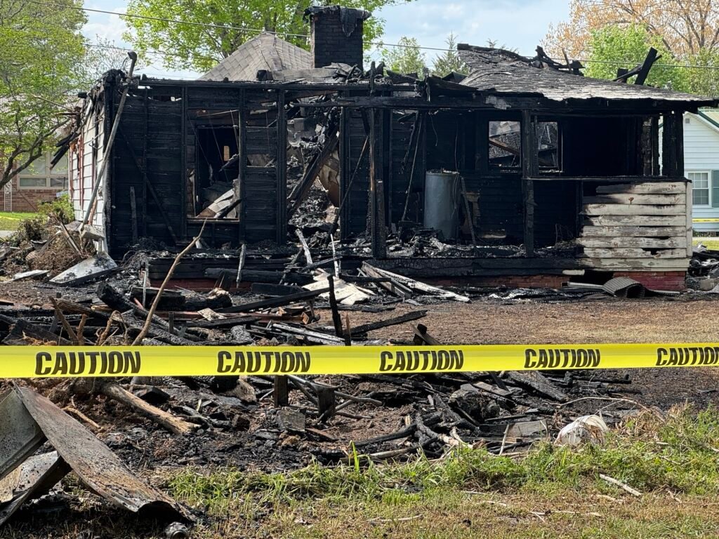 The charred remains of a fire-destroyed home behind caution tape in Bruceton, Tennessee.