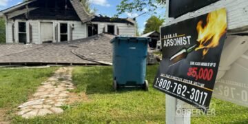 TBI "Burn an Arsonist" flyer on a mailbox with the destroyed home visible in the background.