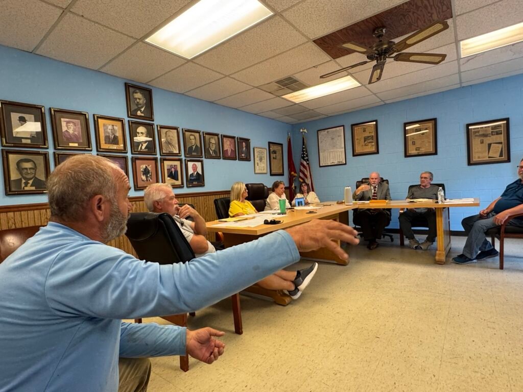 Robert Williams addressing Bruceton board members seated at table during town meeting.