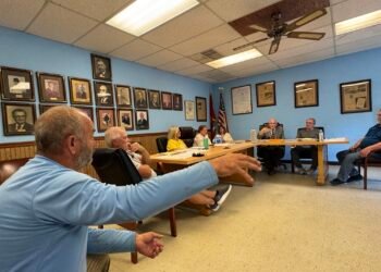 Robert Williams addressing Bruceton board members seated at table during town meeting.