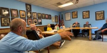 Robert Williams addressing Bruceton board members seated at table during town meeting.