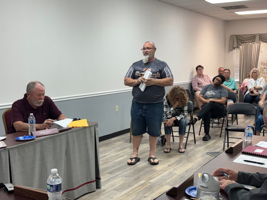 Trezevant resident John Quinn standing and addressing the board at April 2026 meeting with Alderman Mark Argo seated at table.