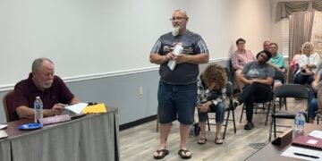 Trezevant resident John Quinn standing and addressing the board at April 2026 meeting with Alderman Mark Argo seated at table.