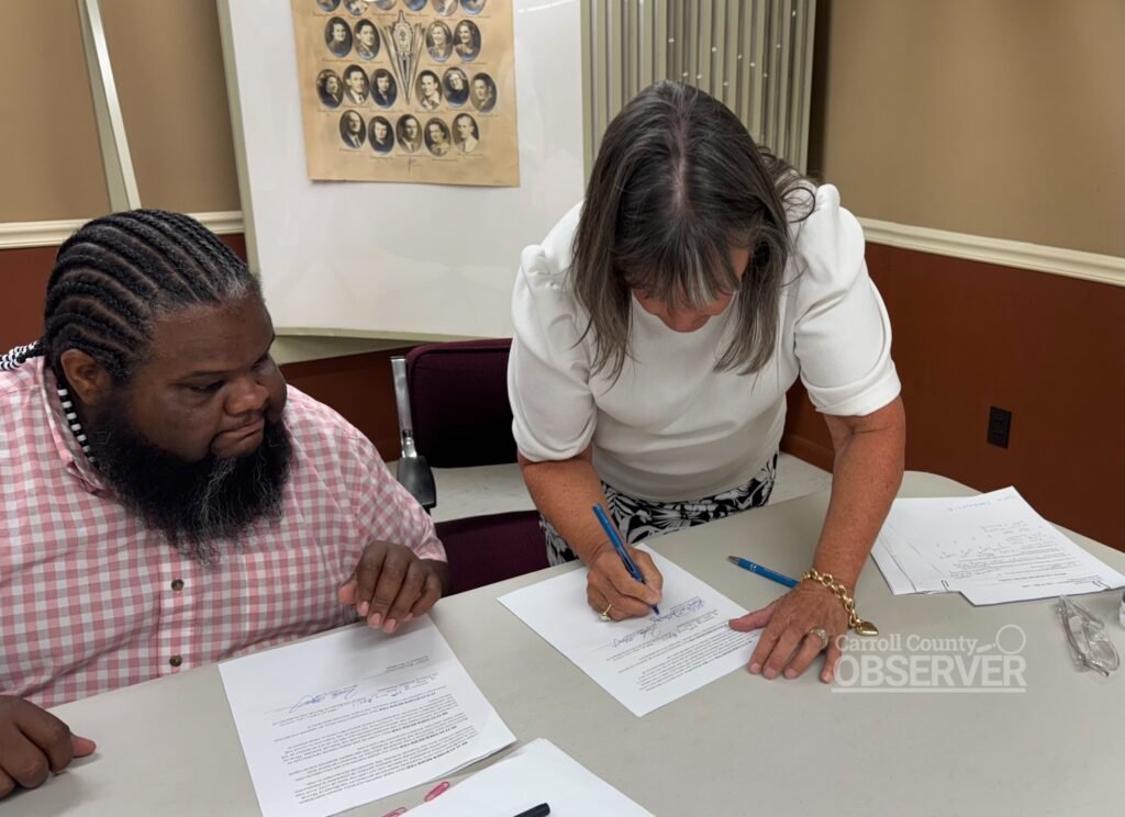 Rita Galloway leans over a table to sign a resolution while Mayor Fridie Algee watches at Atwood City Hall.