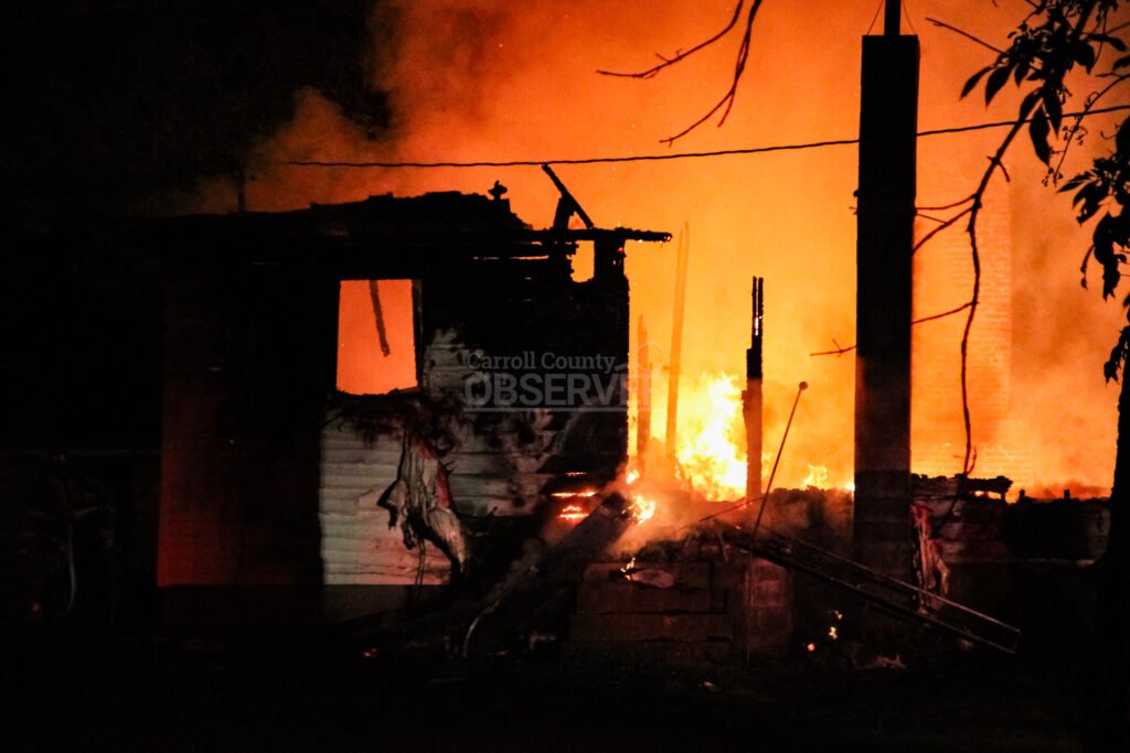 A house fully engulfed in orange flames at night in McKenzie, Tennessee.