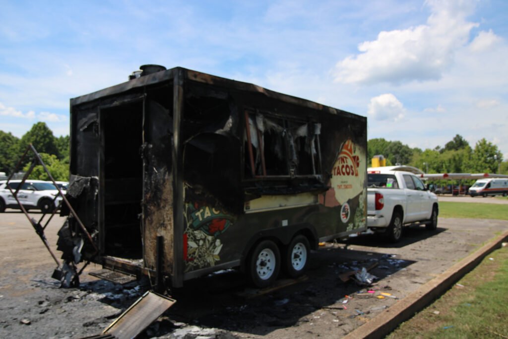 Severely fire-damaged TNT Tacos trailer with blackened exterior and burnt-out interior