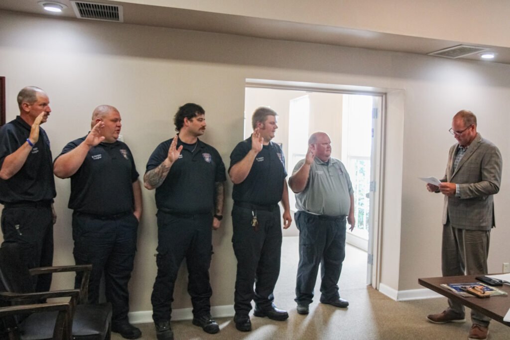 Huntingdon Mayor Chad Edwards administers the firefighter's oath to five Huntingdon firefighters with raised hands at Huntingdon City Hall.