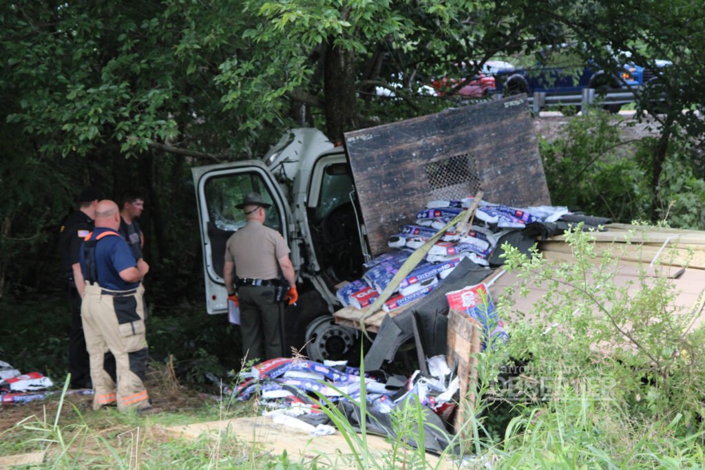 Tennessee Highway Patrol trooper and first responders inspect a wrecked flatbed truck in Carroll County.