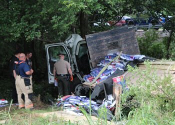 Tennessee Highway Patrol trooper and first responders inspect a wrecked flatbed truck in Carroll County.