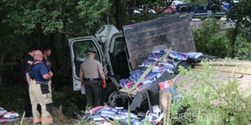 Tennessee Highway Patrol trooper and first responders inspect a wrecked flatbed truck in Carroll County.