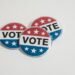 Red, white, and blue voting badges promoting elections on a clean white background.